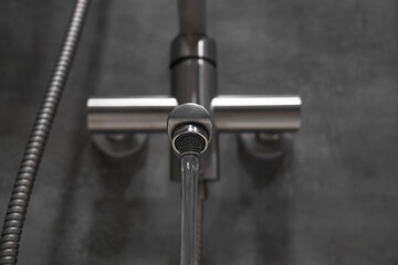 Clean water flowing from a brushed metal faucet aerator in a contemporary bathroom, creating an...