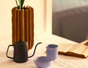 a vase with a flower and a teapot