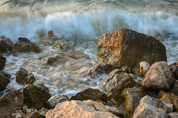 Waves crashing on rocks at sunset, long exposure seascape photography
