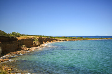 Stunning scenery of ochre cliffs meeting the turquoise sea under a clear blue sky, creating a...