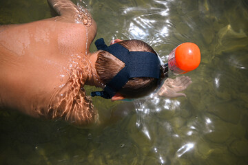 Young adventurer immersing himself in the underwater realm, observing marine life with a snorkel...