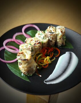 Soya chaap garnished with veggies on a black plate