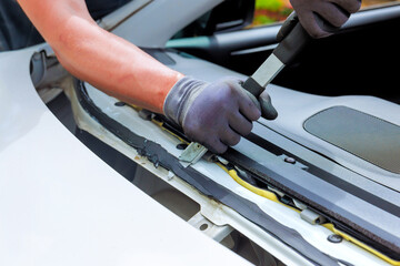 Technician repairs car window seal using pry tool in installation windshield automotive workshop setting
