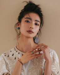 Elegant young woman with stylish earrings poses gracefully.