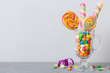 Colorful candies in cup on table on light background background. Large swirled lollipops. Creative...