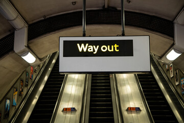 "Way Out" sign on the London Underground with escalator in the background, symbolising exit, travel direction, and iconic UK transport design.