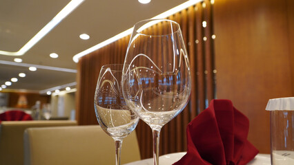Two crystal-clear wine glasses placed elegantly on a finely set dining table with a luxurious...
