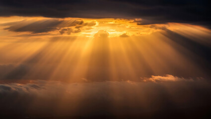 Dramatic golden sunlight breaking through dark clouds creating stunning atmospheric rays of light and heavenly sky