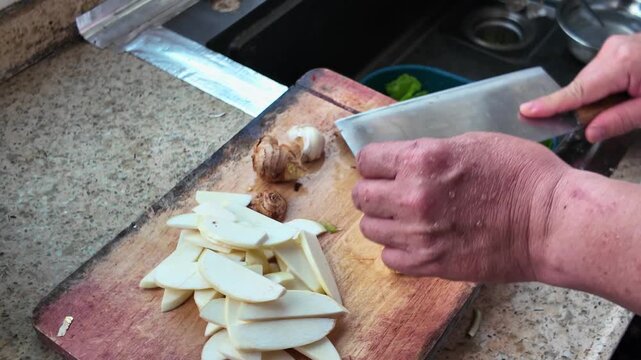 A chef peeling and chopping garlic