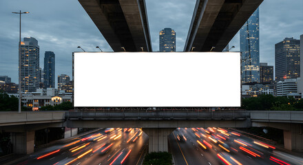 Blank white billboard mockup over a busy highway with long exposure traffic trails against a modern city skyline at dusk.