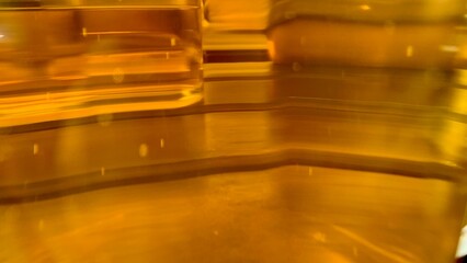 A close-up view captures the captivating play of light on a golden liquid. The fluid's warm hue creates an inviting atmosphere, emphasizing its silky texture