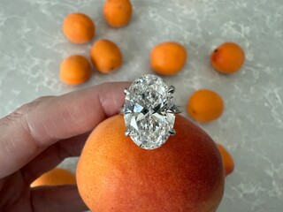 Macro view of an oval cut diamond engagement ring placed atop an apricot, positioned on a textured...