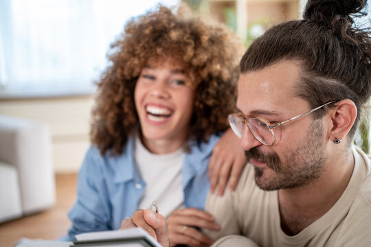 Young couple planning and laughing together at home - Powered by Adobe