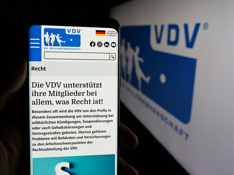Stuttgart, Germany - 08-07-2025: Person holding cellphone with webpage of Vereinigung der Vertragsfu&szlig;ballspieler (VDV) on screen in front of logo. Focus on center of phone display.