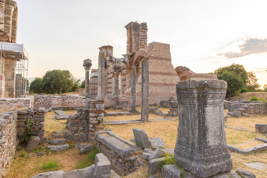 Interior ruins of Basilica B in Philippi, with preserved columns, arches, and decorative stonework under the sunset light