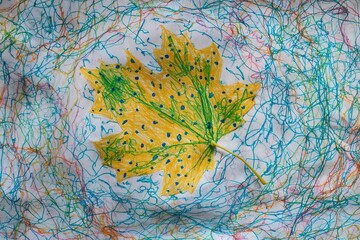Colorful leaf art created using a yellow leaf on textured paper with vibrant sketches during a creative session at home