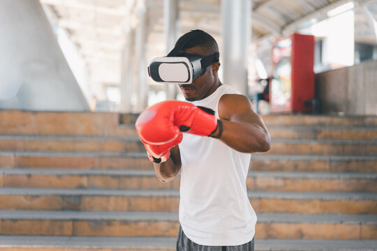 Focused Black athlete wearing VR headset and red boxing gloves trains with precision outdoors. Showcases virtual reality integration in fitness, interactive training, and high-intensity workouts.