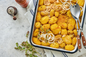 Roasted crushed baby potatoes garnished with fresh herbs and onions in rustic enamel tray kitchen...