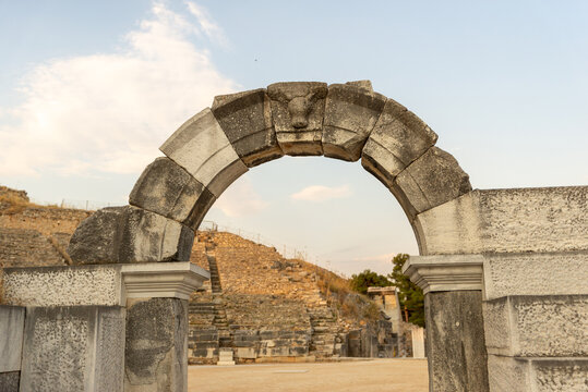 Ancient Roman stone arch at the entrance of the theatre of Philippi, with carved keystone and arena in the background