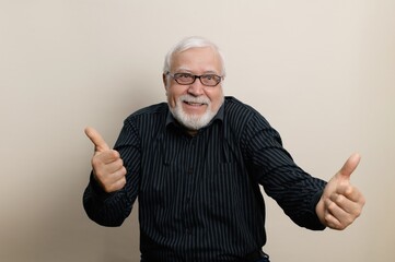 Senior man smiling and giving thumbs up in a cheerful indoor setting with neutral background during...