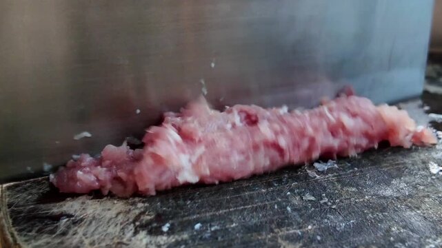 A chef is cutting pork and mincing meat