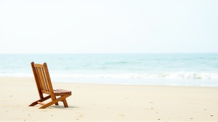 An empty wooden beach chair awaits on a sandy shore, facing a tranquil ocean view.