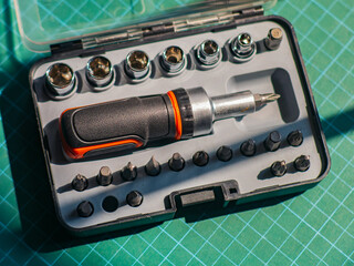 Close-up of a screwdriver set with multiple interchangeable bits and sockets in a plastic case,...