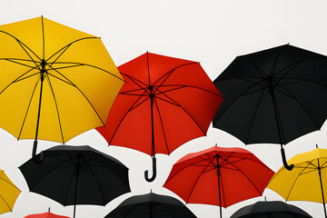 Obraz premium Yellow red and black umbrellas open against white sky, colorful parasols overlapping in vibrant outdoor arrangement, weather protection accessories concept, artistic rain shelter pattern for design an