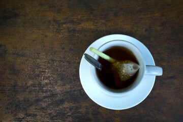 A cup of herbal drink with lemongrass and tea, ginger, honey on an old wooden table