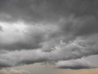 Dark grey clouds at sunset time.gllomy sky with dark gray clouds.Aerial view over the dramatic clouds.Dramatic panorama sky with storm cloud on a cloudy day. Panoramic image. 