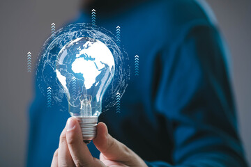 A person holds a glowing light bulb with a digital world map, symbolizing innovation, technology, and global connectivity.