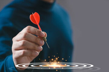 A person holding a red dart, ready to throw it towards a target, symbolizing focus and precision in a sophisticated setting.