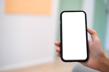 A hand holding a blank smartphone in a well-lit indoor setting, ready for customization or displaying content.