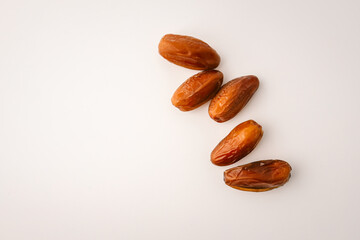Top view of five dried dates arranged diagonally on a light cream background. Simple organic food...