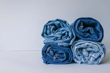 A stack of rolled blue and beige jeans on a neutral background, perfect for minimalist fashion...