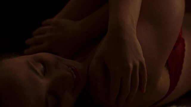 A beautiful woman wearing enticing lingerie sensually caressing her attractive body in slow motion