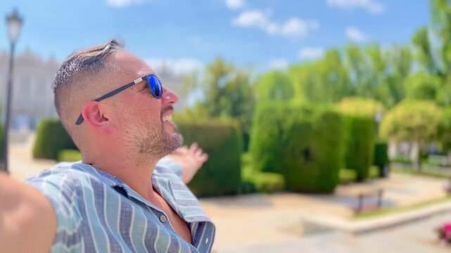 POV Point of view of male latin cheerful traveler tourist spreading arms wide basking in summer freedom near Royal Palace of Madrid experiencing vibrant Spanish cityscape with pure joy and relaxation.