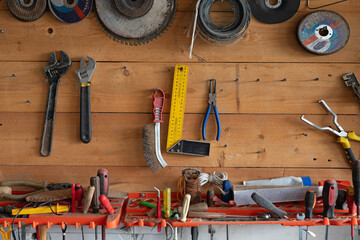 A wooden wall in the garage with tools and other accessories. Screwdrivers, wire cutters, and sanding discs. All the trappings of a man in the garage