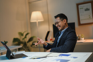Asian businessman having video call on tablet in office at night