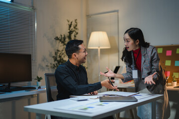 Asian businesspeople arguing about project late at night in office