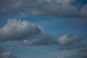 Blue sky with dramatic white and grey cumulus clouds. A natural weather and nature background.