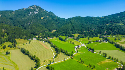 Aerial panoramic view of Zgornje Jezersko valley with lush green meadows, winding roads, and...