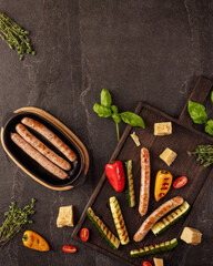 Grilled sausages served with rustic zucchini, bell peppers, cherry tomatoes and cheese cubes on a...