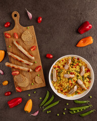 sausage and vegetable rice bowl with breadsticks and crackers, fresh bell peppers, cherry tomatoes,...