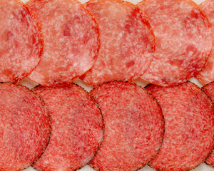 Italian sliced salami arranged in rows on a white background, close-up food texture, fresh gourmet...