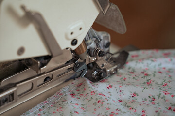 A seamstress works on a production sewing machine at an enterprise, sewing bed linen