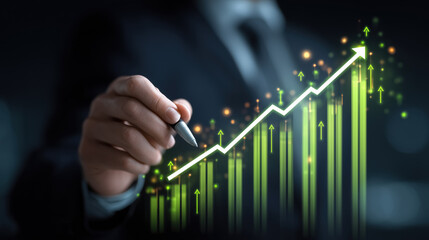 Businessman in suit with stylus or pen pointing at upward-trending line graph, glowing digital chart with green bar graphs. Concept of financial analysis, investment growth, data-driven strategy. 