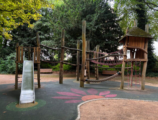 Kids playground in city park with slide, climbing nets, rope bridges and trees around. Fun...