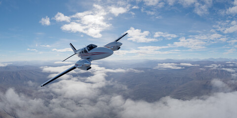 Small Twin-Engine Airplane Flying Over Mountainous Landscape in Clear Skies
