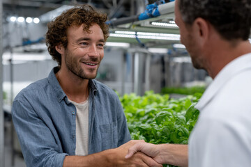 A different angle capturing a young man shaking hands with another individual in a lush indoor garden, highlighting the importance of collaboration and nature’s beauty in professional settings.